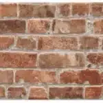 Mosaïque de carreaux muraux imitation brique rustique, tons rouge-brun mélangés, avec joints gris clairs, style ancien et texturé.