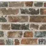 Mosaïque de carreaux muraux aspect brique vieillie et rustique, tons terreux, gris, et rouge-brun, avec mortier apparent.