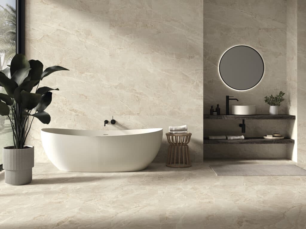 Salle de bain moderne luxe avec baignoire îlot, carrelage effet marbre beige, miroir rond rétroéclairé et plantes.