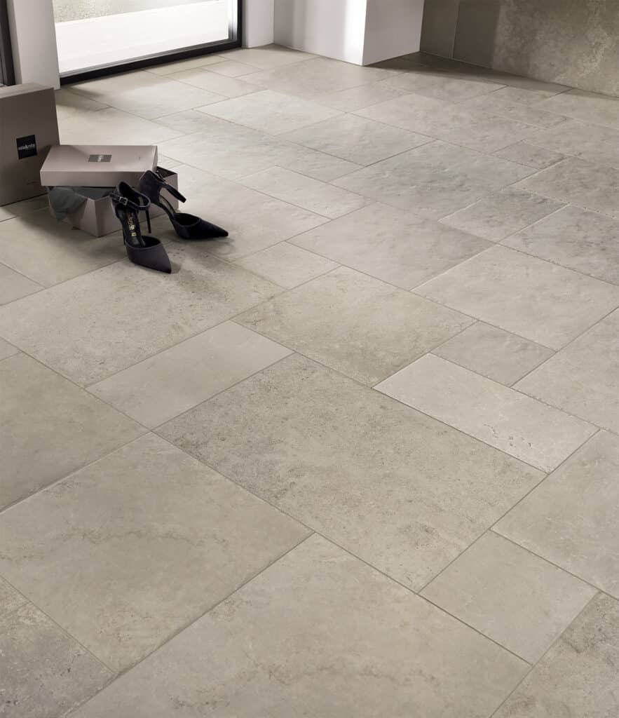 Paire d'escarpins noirs 'nila&nila' sur un sol en grands carreaux de pierre naturelle beige clair.