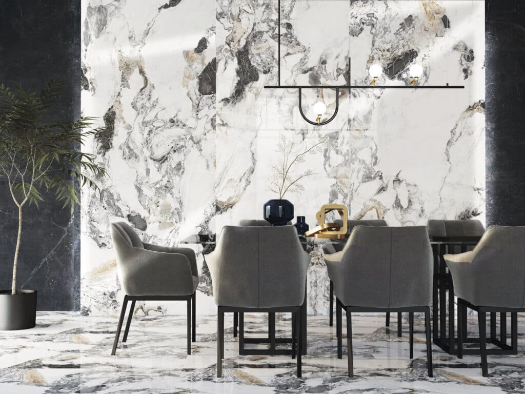 Salle à manger moderne avec murs et sol en marbre blanc veiné de gris et or, éclairée par un luminaire noir, entourant des chaises grises.