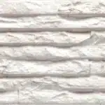 Texture murale en pierre ou brique décorative blanche veinée de gris, avec des reliefs horizontaux et une apparence rustique et brute.