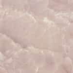 Texture translucide et veinée d'onyx rose pâle, évoquant un marbre doux avec des zones cristallines et des nuances de blanc cassé.