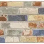 Mur de briques ou carreaux de parement style rustique, effet pierre, avec un mélange de couleurs pastel et vives (bleu, ocre, vert, terre cuite) et joints gris clairs.