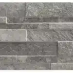 Revêtement mural en pierre naturelle ou ardoise grise, style patchwork ou parement mince, avec textures rugueuses et nuances variées de gris foncé et moyen.