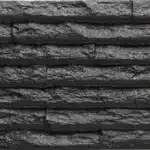 Texture de parement mural en pierre sombre ou ardoise noire, présentant des bandes horizontales rugueuses et stratifiées, aspect rocheux brut.