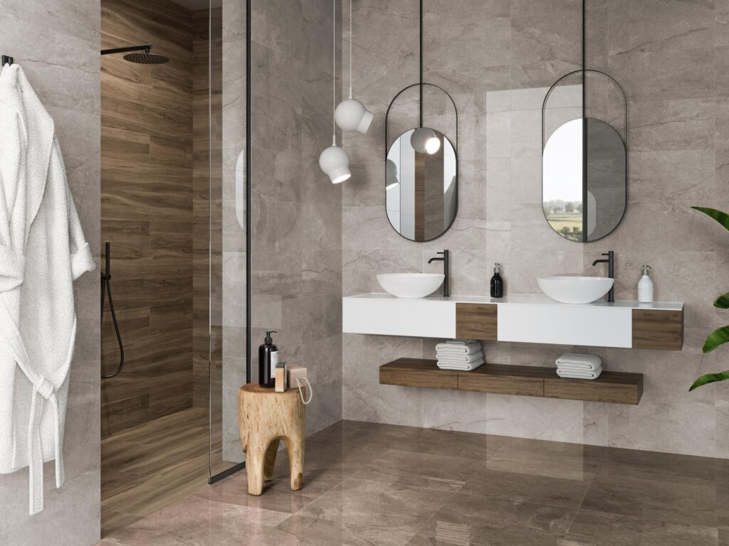 Salle de bain moderne avec murs en marbre gris, douche à effet bois et double vasque flottante. Peignoir blanc sur la gauche.