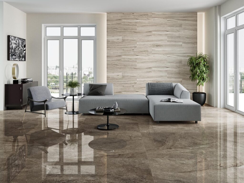 Salon moderne avec canapé sectionnel gris, fauteuil d'appoint, tables basses noires et sol en carrelage poli marron réfléchissant, mur d'accent effet bois clair.