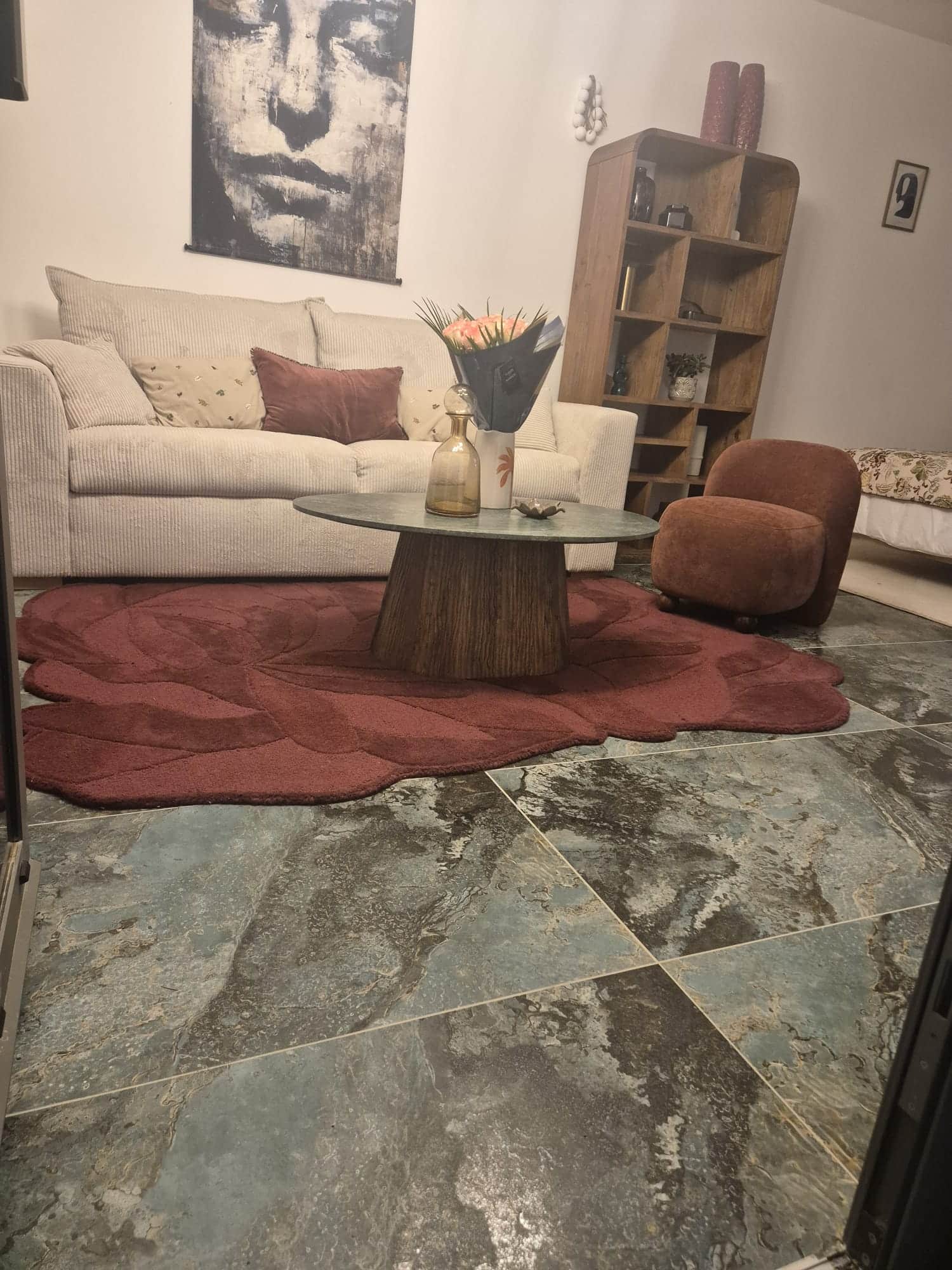 Salon moderne avec canapé blanc, tapis rose bordeaux, table basse ronde et carrelage marbré.