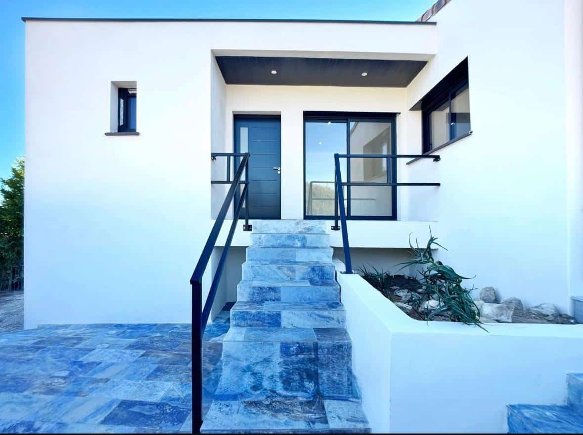 Escalier en pierre bleue menant à l'entrée d'une maison moderne blanche avec rambardes noires.